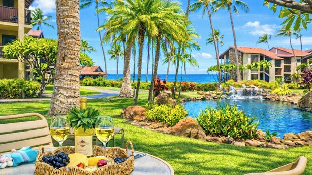 Una località turistica tropicale con piscina, palme e zona ristorazione con tavolo apparecchiato per due.