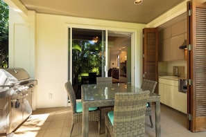 Un patio con una parrilla, mobiliario de mimbre y vistas al exterior.