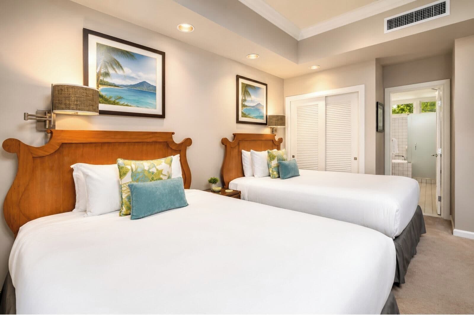A hotel room with two beds, a large window, and a door leading to a bathroom.