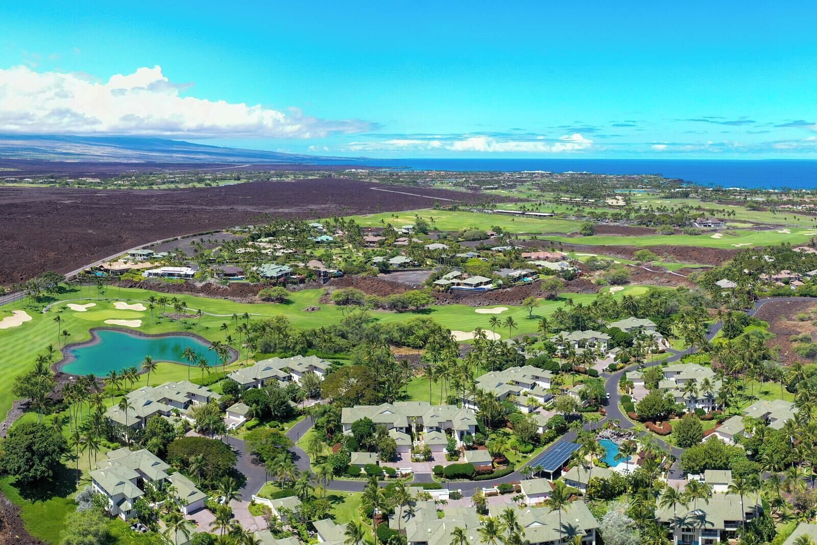 Un campo de golf con edificios residenciales, una piscina y vista despejada al océano.