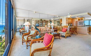 Amplia sala de estar con muebles de mimbre, televisor y vista al océano.