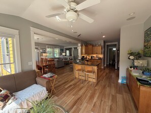 A spacious living area with a dining table, a sofa, and a kitchen in the background.