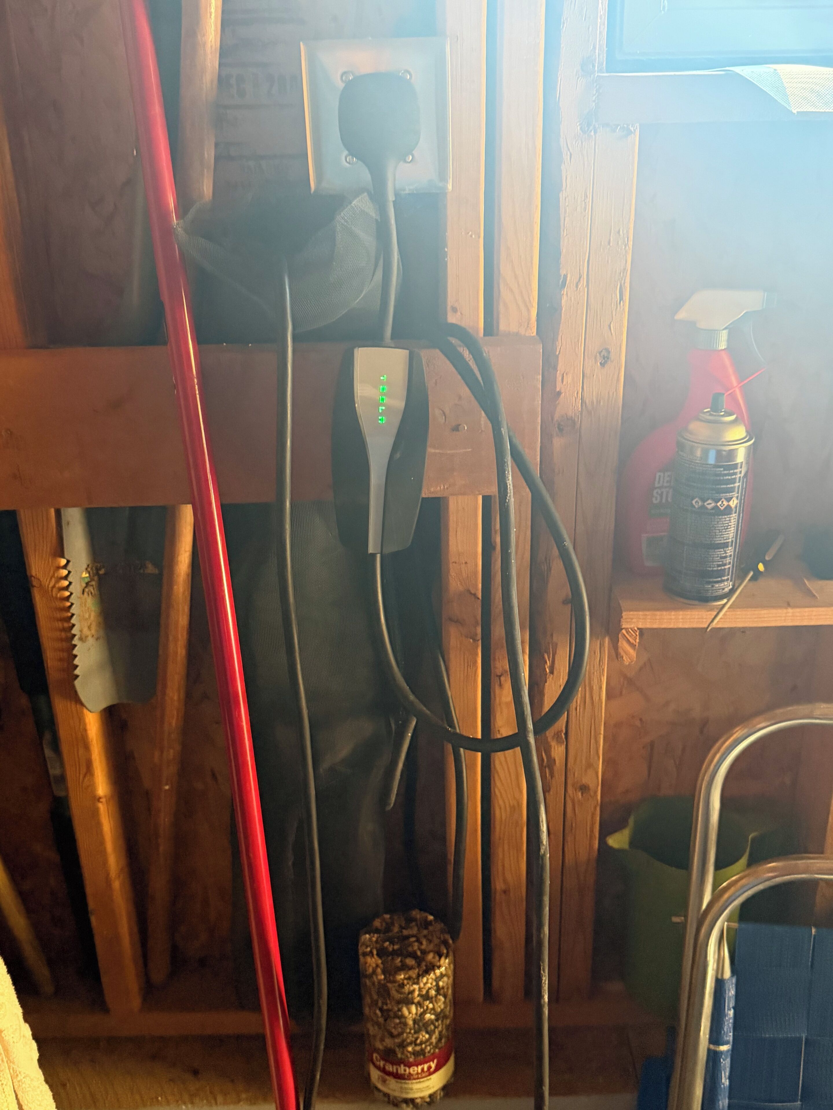 Un intérieur en bois avec un tuyau rouge, un outil en métal et un bidon posé sur une étagère.