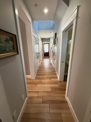 A hallway with wooden flooring, white walls, and a ceiling light.