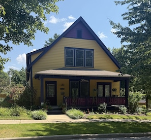 A two-story house with a gabled roof, a front porch, and a number '1327' on the door.