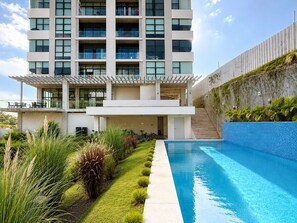 Ein modernes Hotel mit Pool, überdachtem Außenbereich und einer Treppe zu den oberen Etagen.