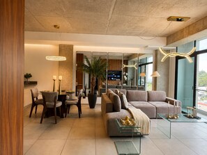 Ein modernes Wohnzimmer mit einem Glastisch, einer Couch und einem Essbereich mit Stühlen und einem kleinen Tisch.