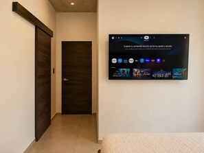 Ein Hotelzimmer mit einem großen, an der Wand befestigten Flachbildfernseher, der verschiedene Streaming-Dienste anzeigt.