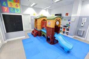 Ein Spielbereich mit Rutsche und Klettergerüsten, einer Tafel und bunten Zahlenkacheln an der Wand.