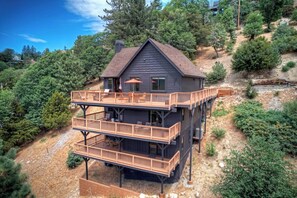 A multi-level wooden cabin with a deck, surrounded by trees and a clear sky. - Eagles Peak. Lake Arrowhead Modern Lake View Lodge. Pool Table AC Panorama Views (Lake Arrowhead)