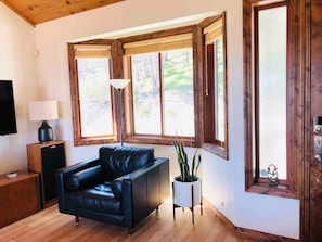 Quarto com sofá de couro preto, luminária, mesinha e planta em vaso.