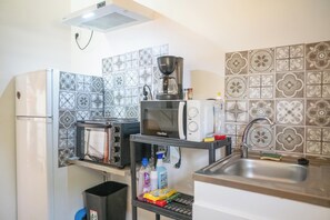 A compact kitchen with a refrigerator, microwave, toaster, and a coffee maker. - Colline - Proche plage - Terrasse (Le Moule)