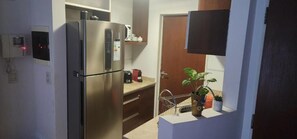 A compact kitchen with a stainless steel refrigerator, a microwave, and a small countertop. - Aparts Temporarios (Buenos Aires)