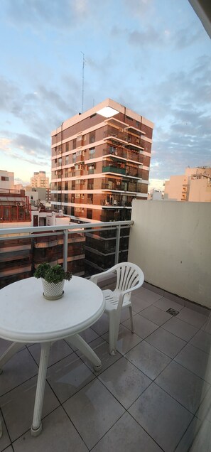 A rooftop terrace with a round table and chairs, a potted plant, and a view of a multi-story building. - Aparts Temporarios (Buenos Aires)
