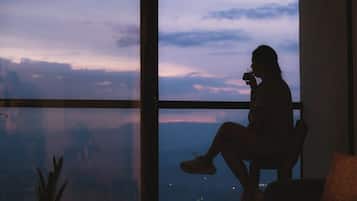 Una persona sentada junto a un amplio ventanal con vistas al cielo y luces distantes.