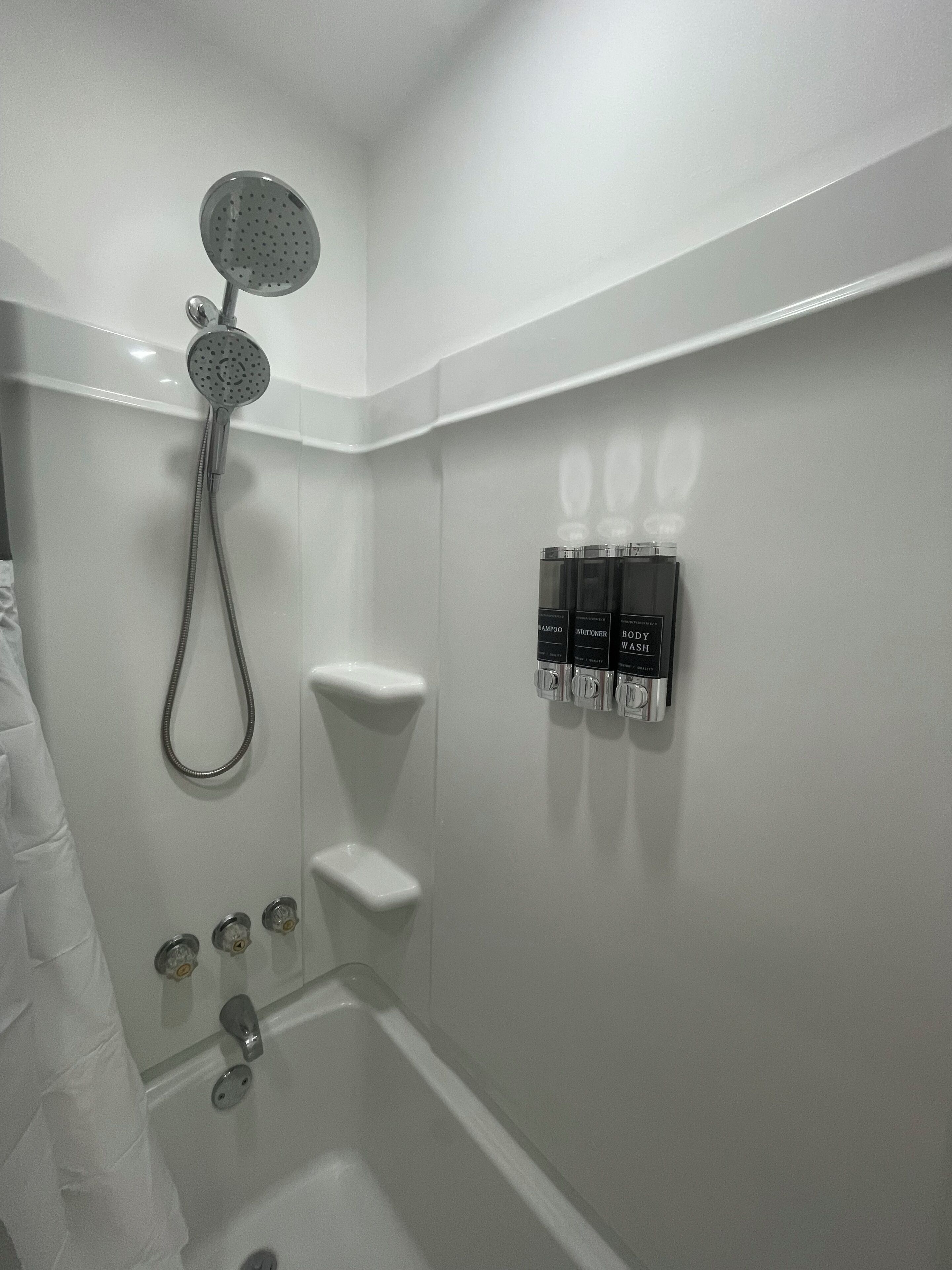 Un baño moderno con ducha, inodoro y dispensador de pared.
