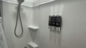 Un baño moderno con ducha, inodoro y dispensador de pared.