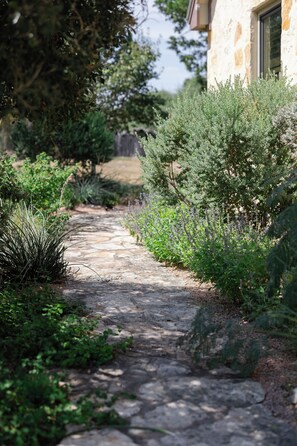 A stone pathway leading through a garden with various shrubs and plants. - Private 14 Acre Estate on Barton Creek with Two Homes, Pool and Multiple Gardens (Austin)