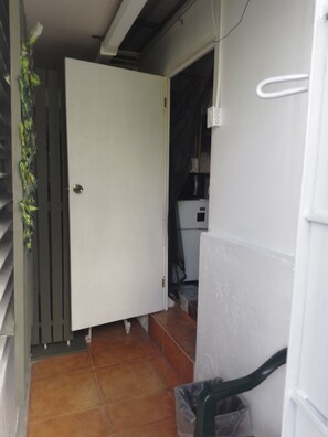 A room with a white door, a tiled floor, and a white wall.