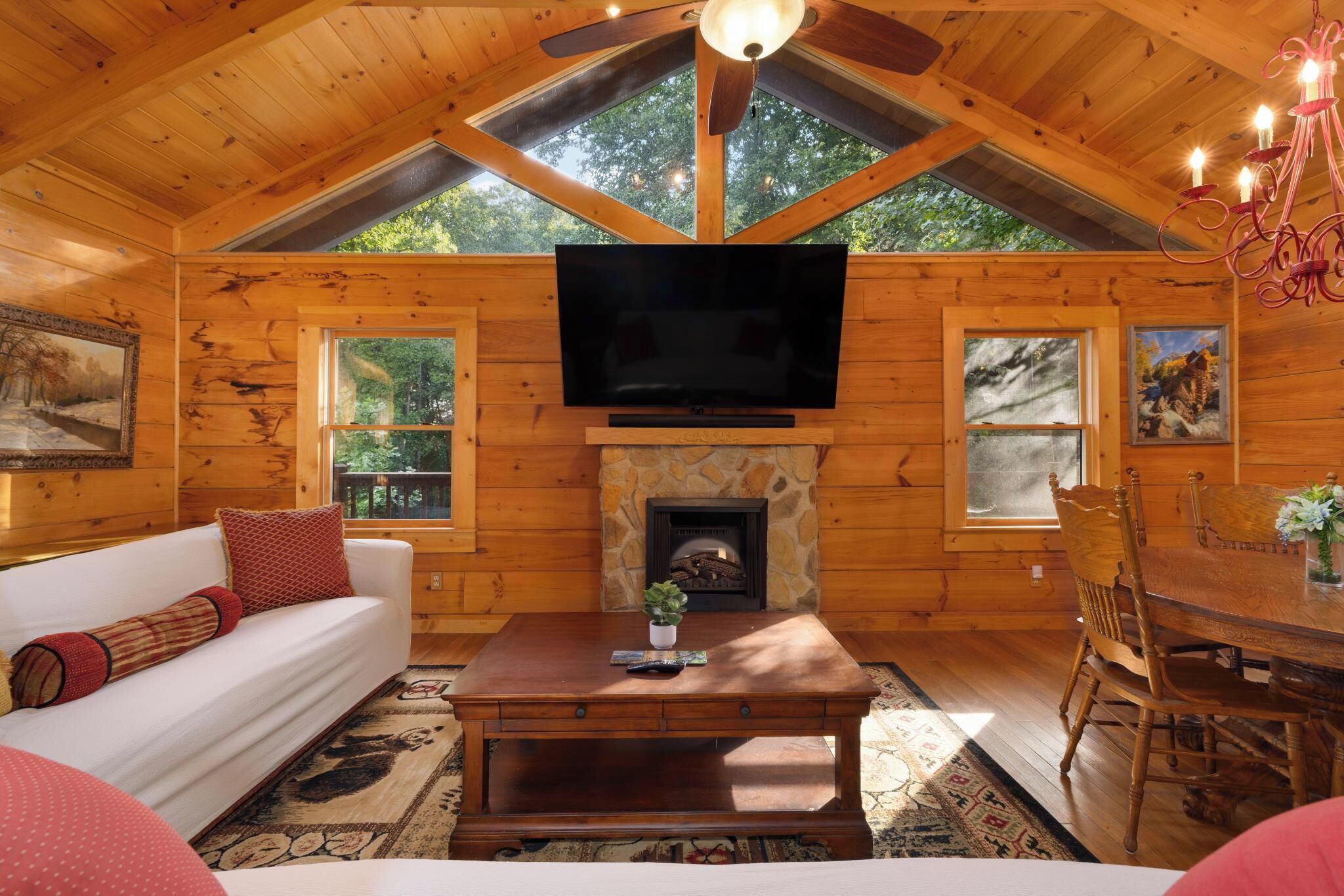 Een gezellig chaletinterieur met een open haard, houten wanden, een televisie en een eethoek.