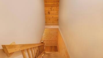 A wooden staircase with a handrail, leading to a landing with a light switch.