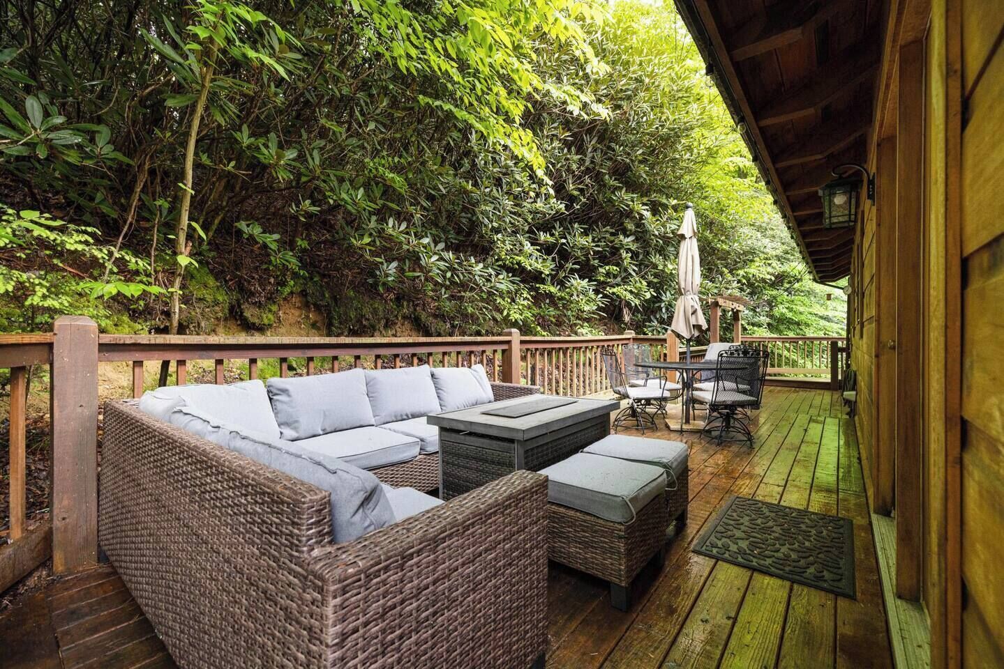 Een houten terras met rieten meubilair, een tafel en stoelen.