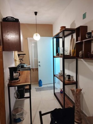 Eine Küche mit einer Kaffeemaschine, Regalen voller Küchenutensilien und einer Pendelleuchte.