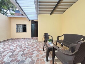 Un patio con piso de baldosas, una mesa con una planta y dos sillas.