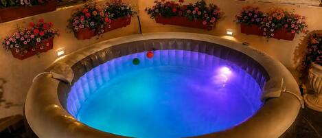 A hot tub with a blue light, surrounded by flower planters.