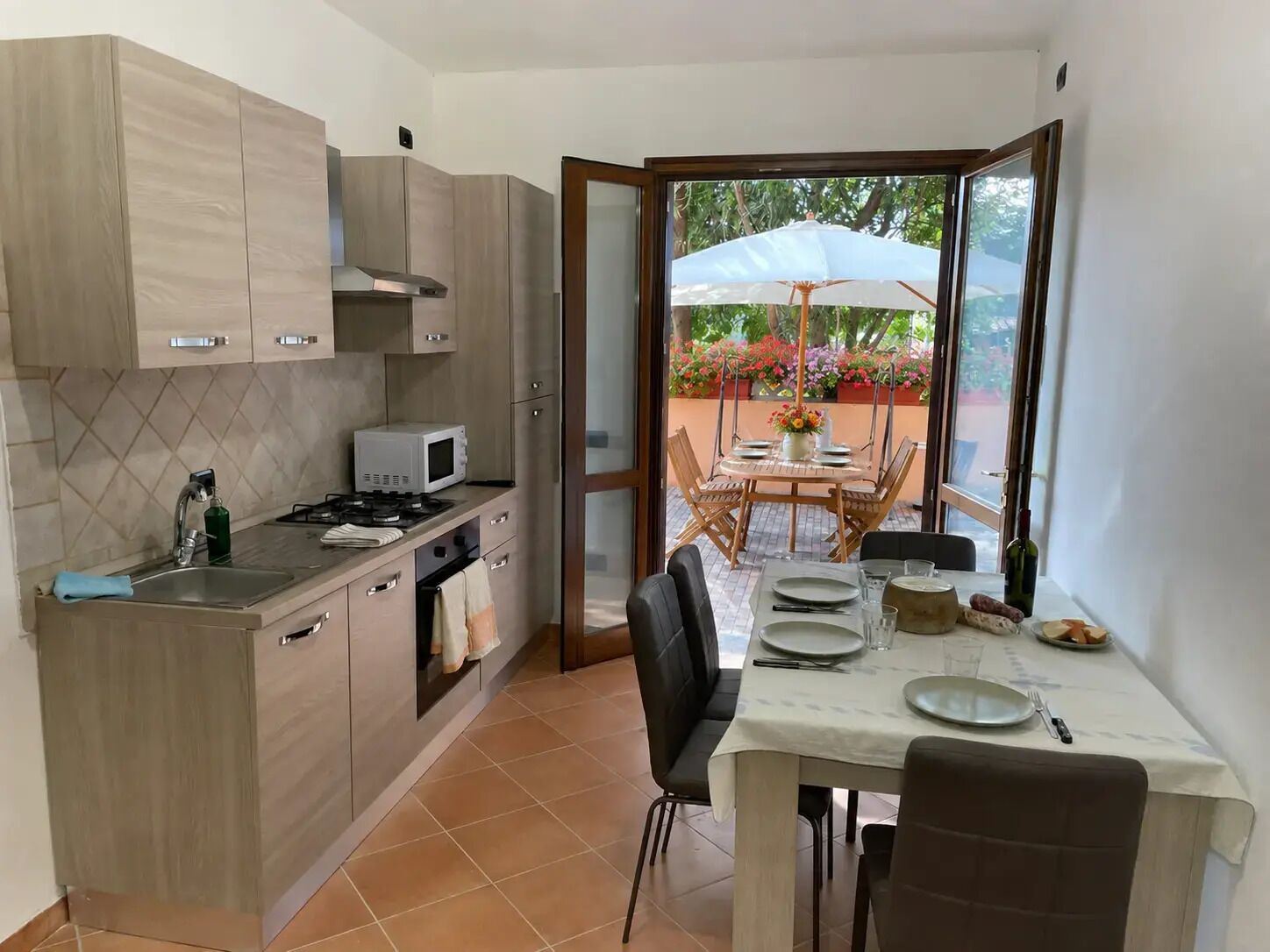 Une cuisine compacte avec un coin repas, une vue sur l’extérieur et une table à manger dressée pour quatre personnes.