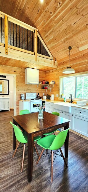 Un interior de madera con una mesa de comedor, sillas, zona de cocina y una escalera.