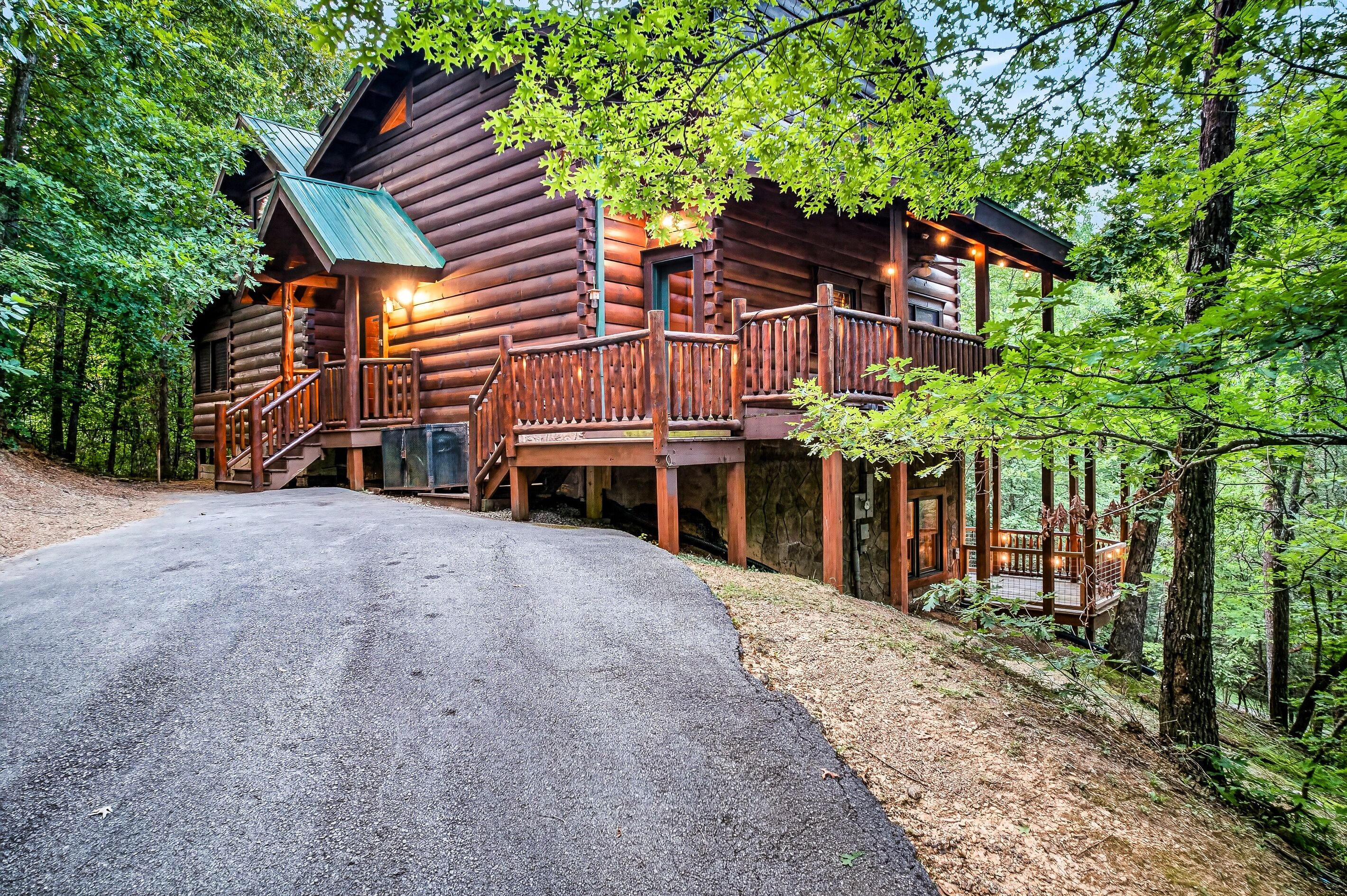 A log cabin with a porch, a staircase, and a driveway leading to the entrance.