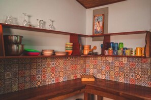 Een keuken met houten planken, een betegelde achterwand en divers keukengerei.