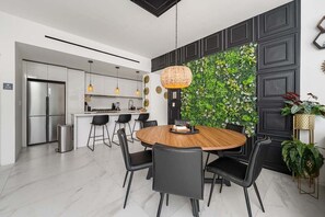 A modern kitchen with a built-in island, stainless steel appliances, and a dining area with a round wooden table and black chairs. - Stunning 2BR Cabo Condo with Pool view & Balcony! (Cabo San Lucas)
