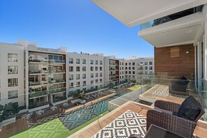 A modern apartment complex with a rooftop terrace featuring outdoor furniture and a swimming pool. - Stunning 2BR Cabo condo with pool view & balcony (Cabo San Lucas)