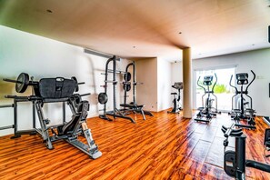 A gym with various exercise equipment, including a squat rack, bench press, and cardio machines. - Stunning 2BR Cabo condo with pool view & balcony (Cabo San Lucas)