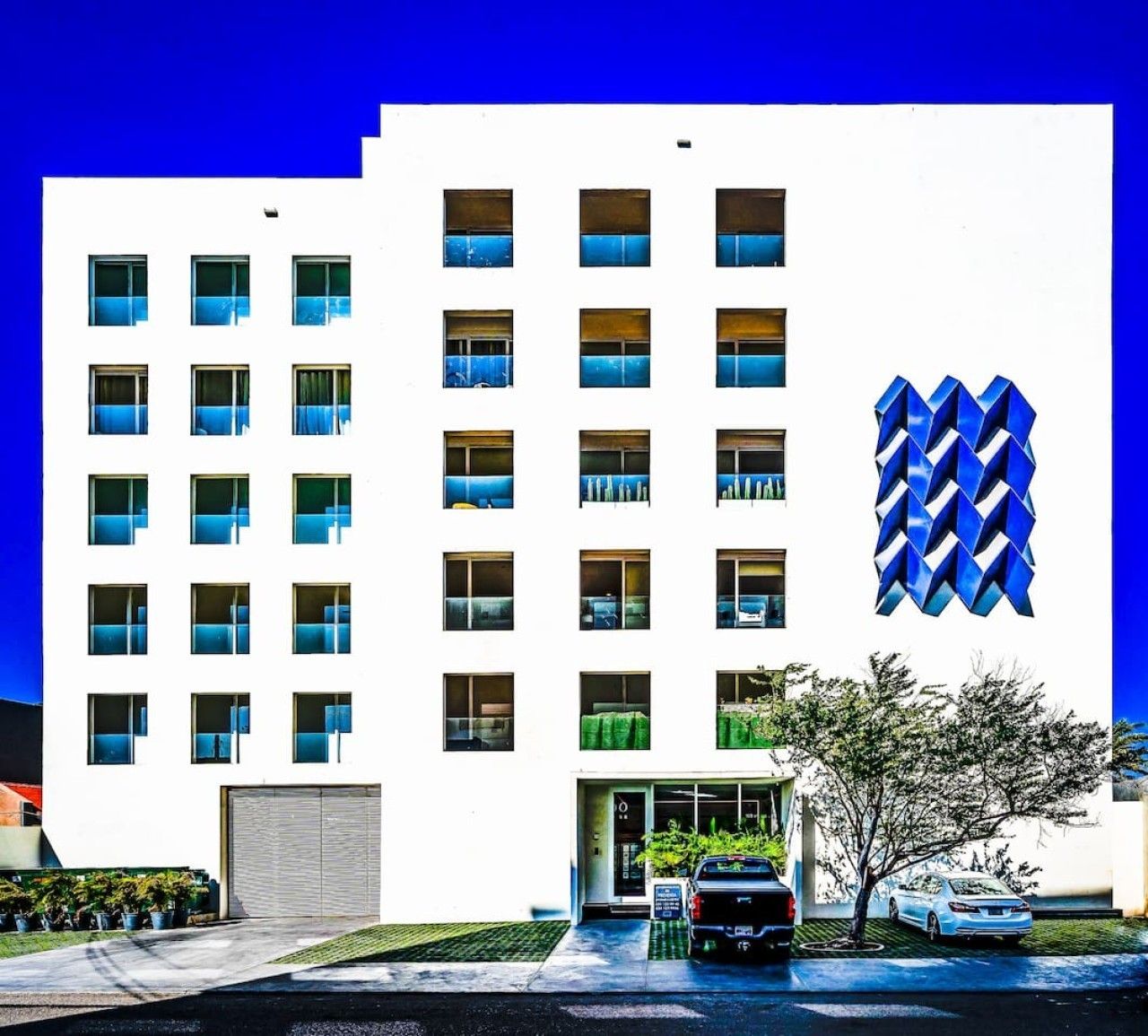 A modern building with a white facade, multiple windows, and a distinctive blue logo.