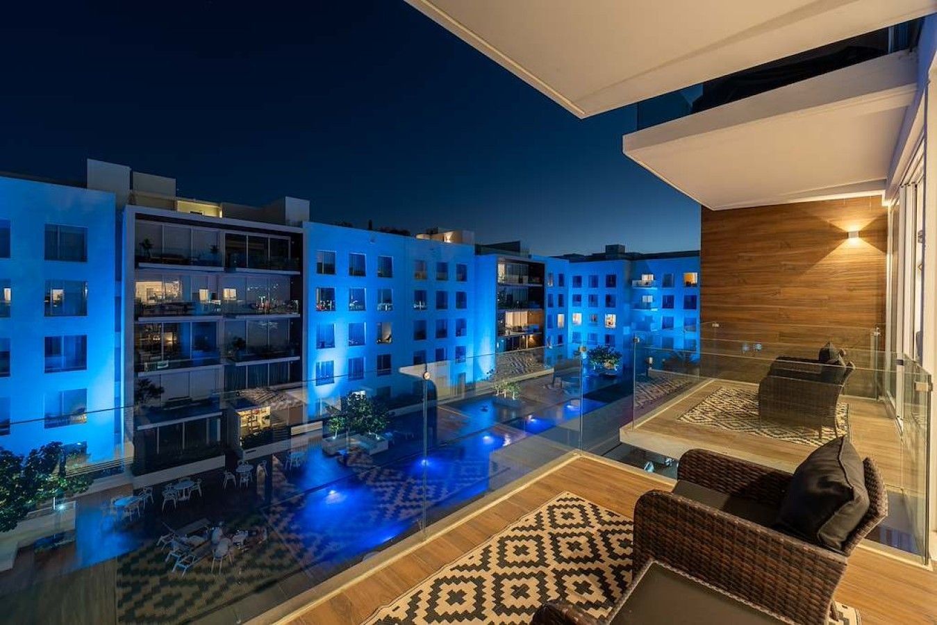 A modern hotel with a rooftop pool area, glass railings, and a view of the surrounding buildings.