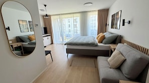 A modern bedroom with a bed, a sofa, a desk, and a large mirror. - Adorable 1-bedroom apartment in beautiful Gerlachov for your stay (Gerlachov)