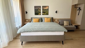 A modern hotel room with a large bed, a seating area, and two landscape paintings on the wall. - Adorable 1-bedroom apartment in beautiful Gerlachov for your stay (Gerlachov)