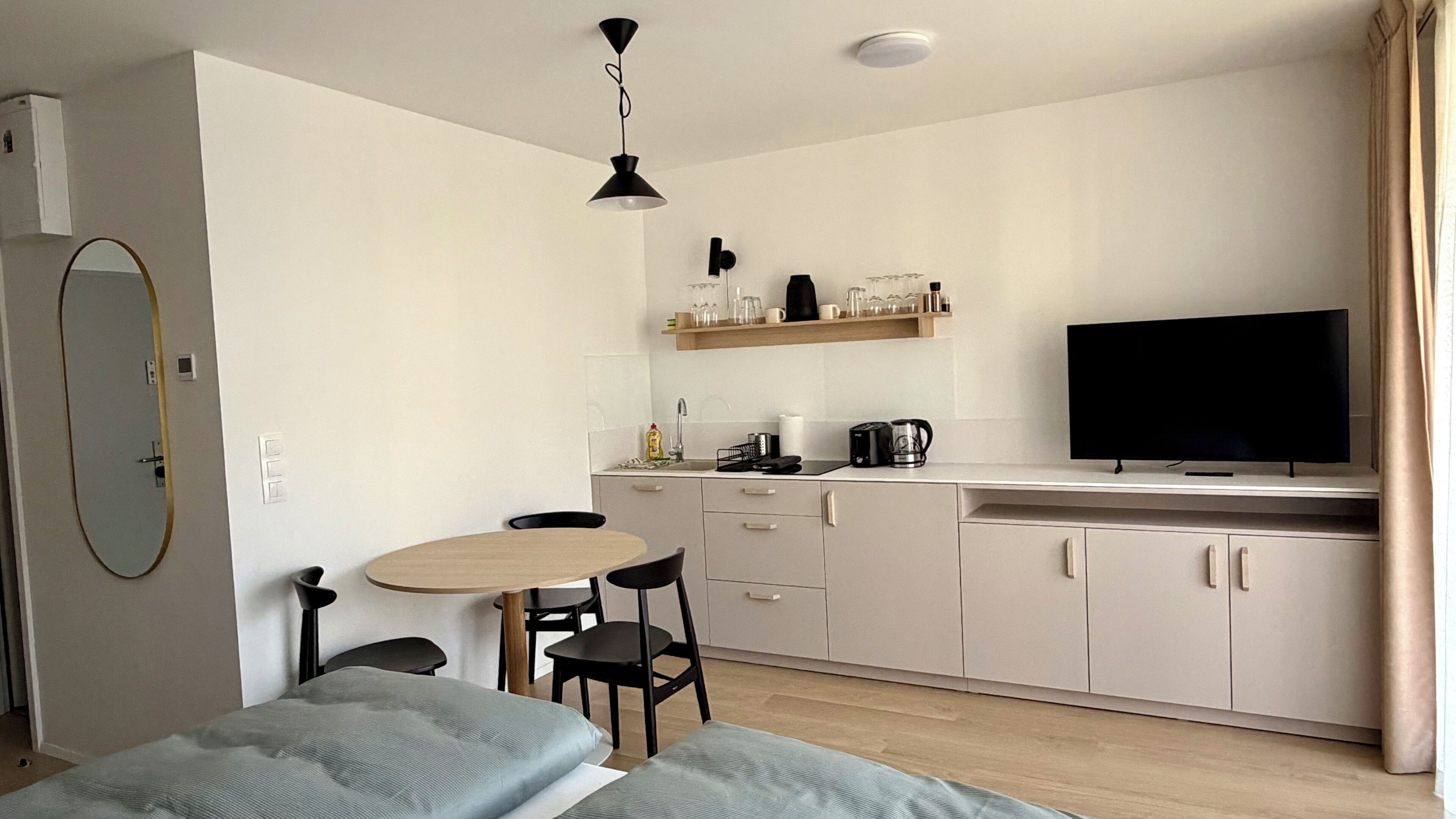 A compact living space with a kitchenette, a dining area, and a TV.