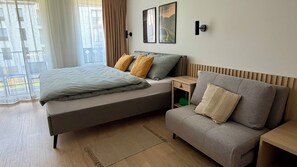 A modern bedroom with a bed, a sofa, a bedside table, and a view of the outdoors. - Adorable 1-bedroom apartment in beautiful Gerlachov for your stay (Gerlachov)