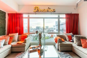 A modern living room with two sofas, a coffee table, and a large window with a city view. - Music City Paradise - 5 min Walk to Broadway (Nashville)