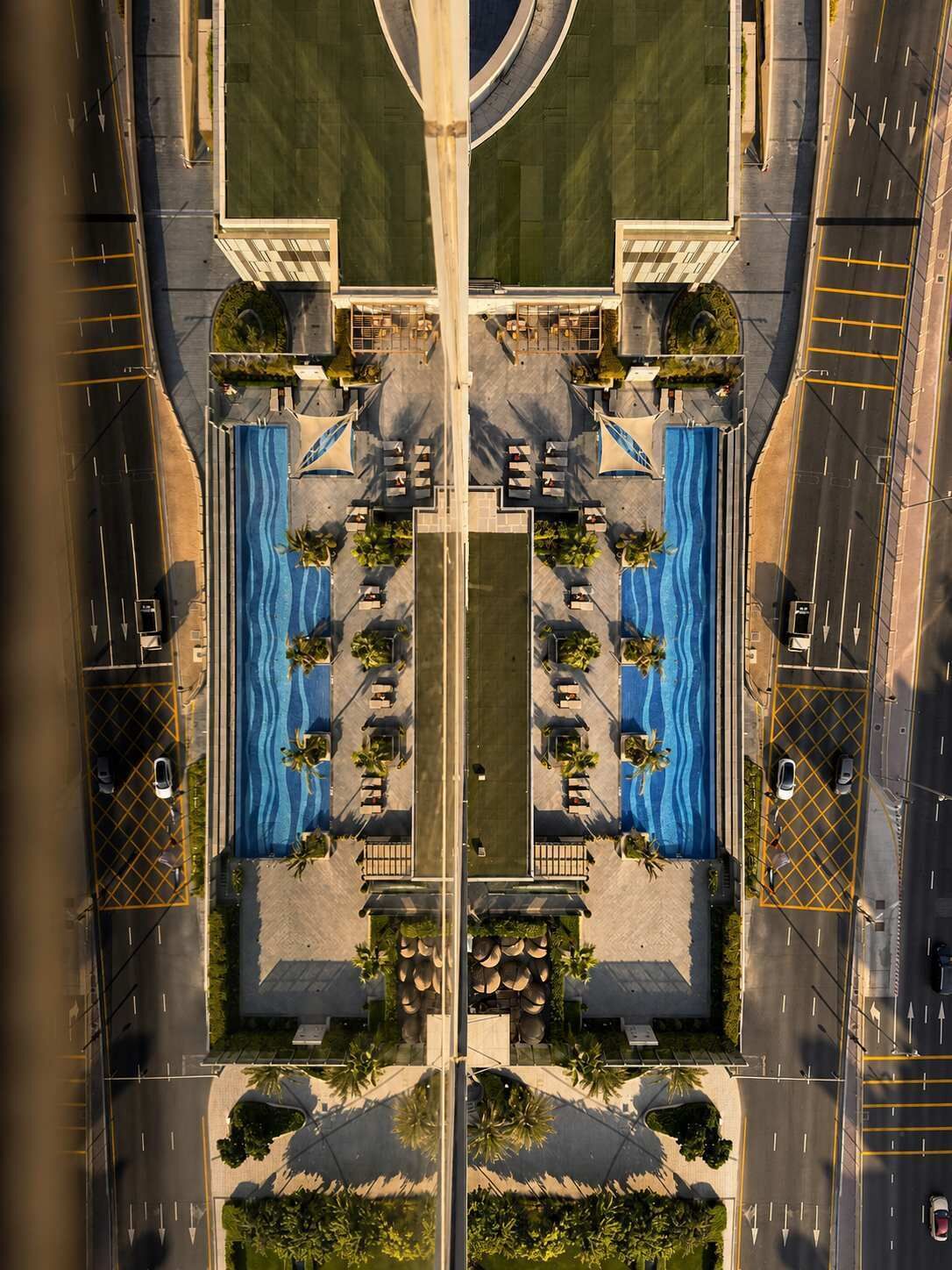Ein symmetrisches Layout mit einem zentralen Pool, Sitzbereichen und einer Straße, die das Grundstück kreuzt.