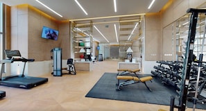 Ein modernes Fitnessstudio mit Cardiogeräten, Kraftstationen und einer Rezeption.