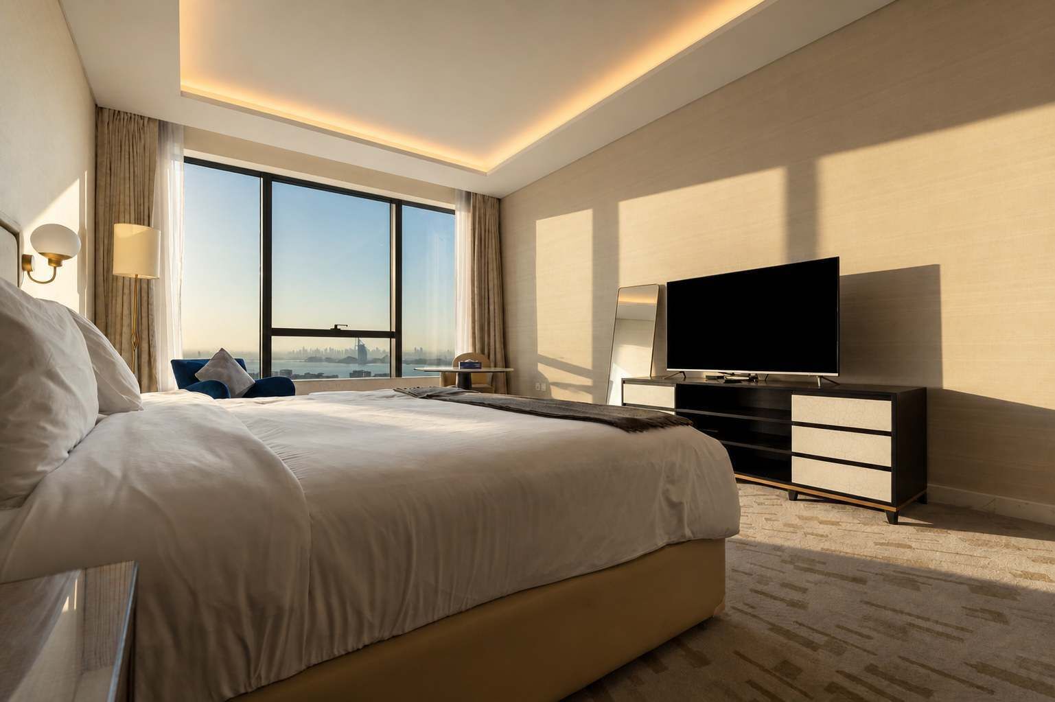 A hotel room with a large bed, a television on a stand, and a view of the city through large windows.