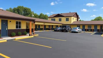 Ein Motel mit mehreren Zimmern, einem Parkplatz und blauem Himmel.