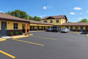 A motel with multiple rooms, a parking lot, and a clear blue sky.