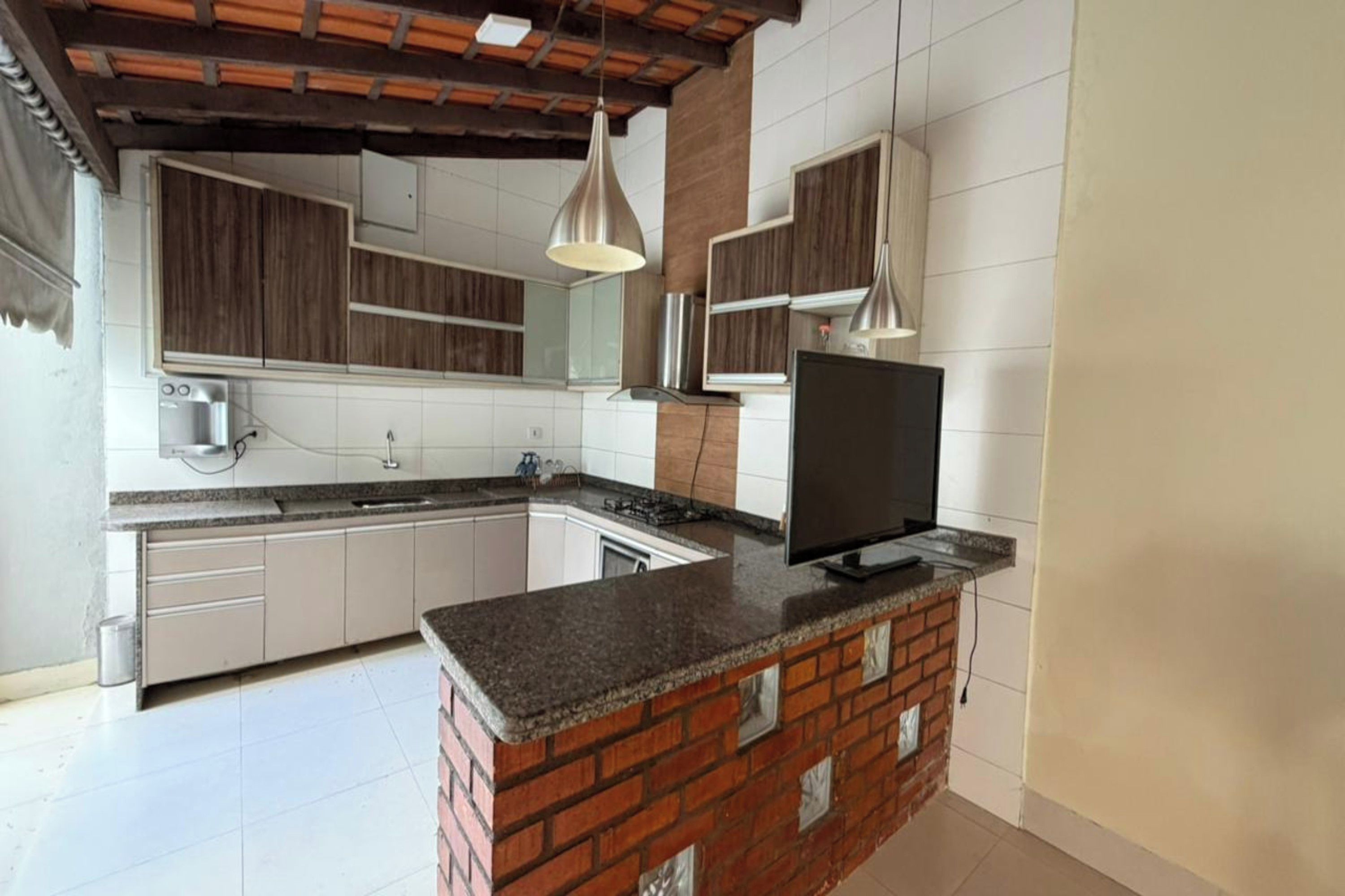 A modern kitchen with a brick island, white cabinetry, and pendant lighting.