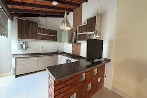 Una cocina moderna con una isla de ladrillo, muebles blancos e iluminación colgante.